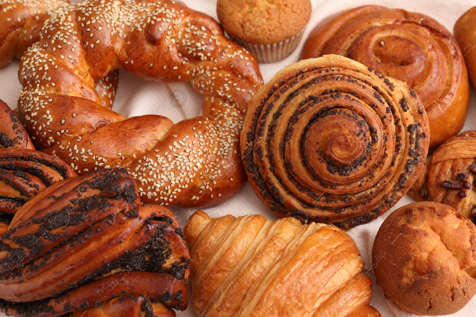 Photo of Different tasty freshly baked pastries on white tablecloth, flat lay