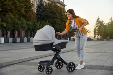 Photo of Young mother walking with her baby in stroller outdoors