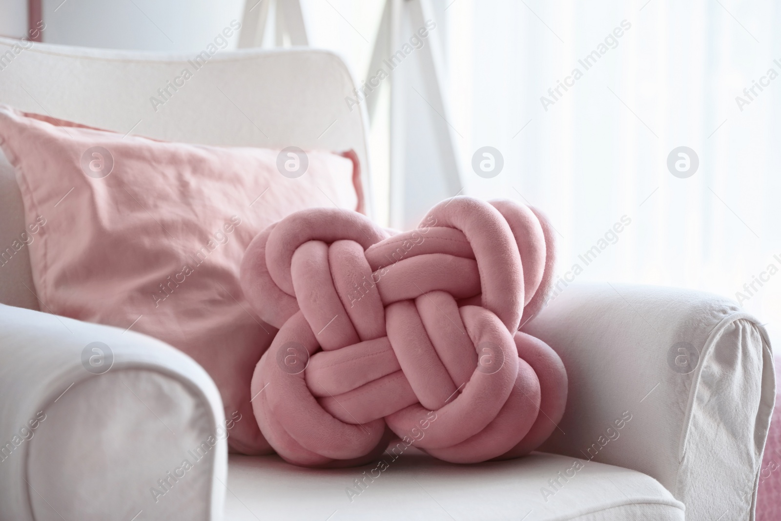 Photo of Pillows on light armchair indoors. Unusual cushion design