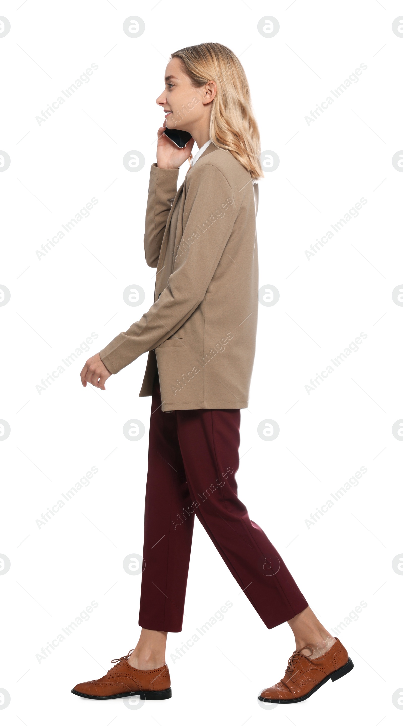 Photo of Young woman talking on smartphone and walking against white background