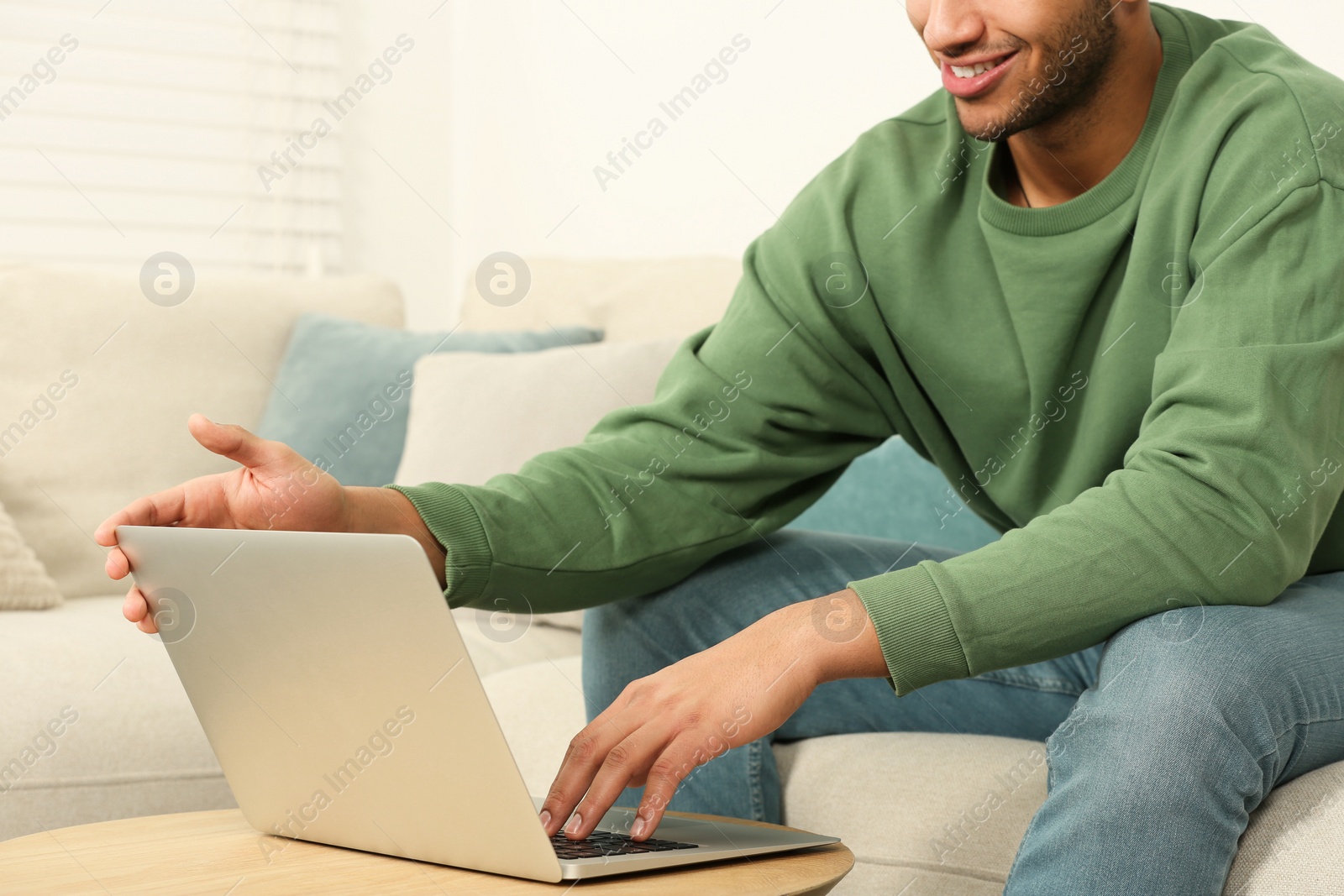 Photo of African American man working on laptop at table indoors, closeup