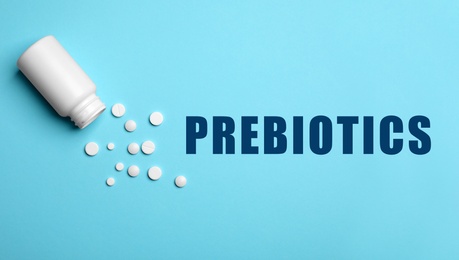 Bottle of pills on light blue background, flat lay. Prebiotic supplements