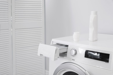 Photo of Washing machine with bottle of detergent in laundry day, closeup