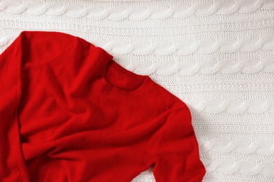 Red cashmere sweater on white knitted plaid. Space for text