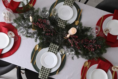 Christmas table setting with festive decor and dishware, top view