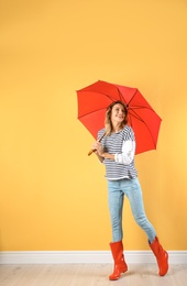 Woman with red umbrella near color wall