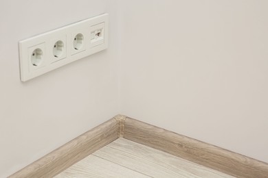 Photo of White wall with sockets and baseboard indoors, space for text