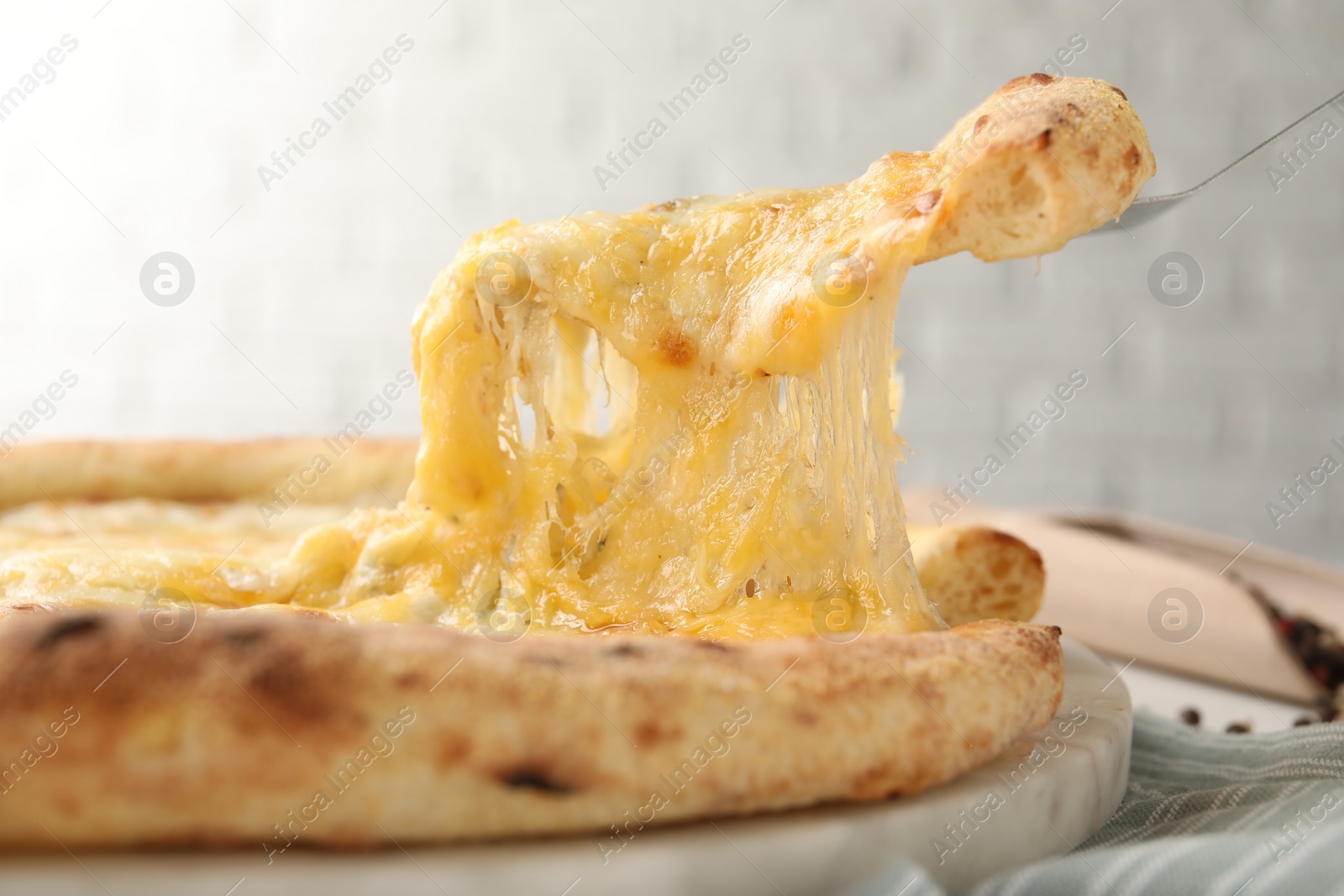 Photo of Taking piece of delicious cheese pizza at table, closeup