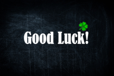 Image of Phrase GOOD LUCK and clover leaf on black background