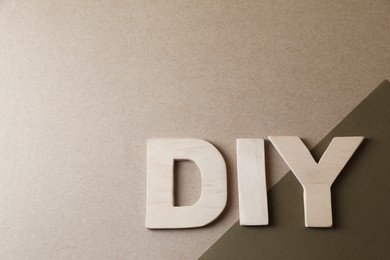 Photo of Abbreviation DIY made of wooden letters on color background, flat lay. Space for text