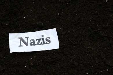 Photo of Paper with word Nazis on soil, top view. Space for text