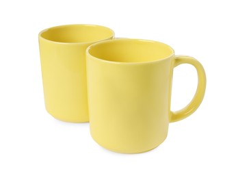 Photo of Two yellow ceramic mugs isolated on white