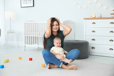 Young mother suffering from postnatal depression and cute baby girl at home