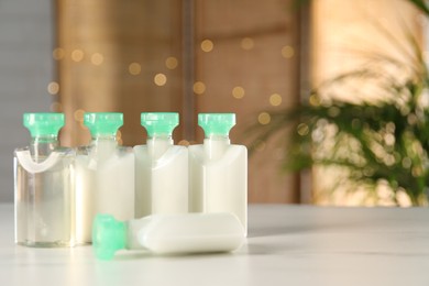 Photo of Mini bottles of cosmetic products on white table against blurred background. Space for text