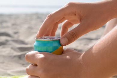 Photo of Woman opening aluminum can with beverage on beach, closeup