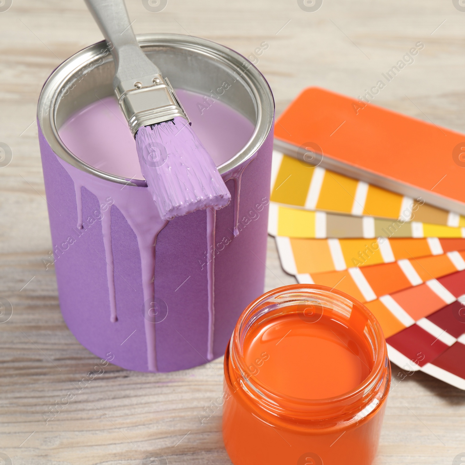Photo of Different paints with brush and palette on light wooden background