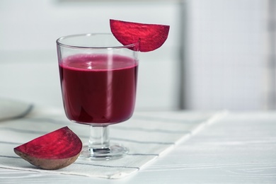 Glass of tasty beet smoothie on table with space for text