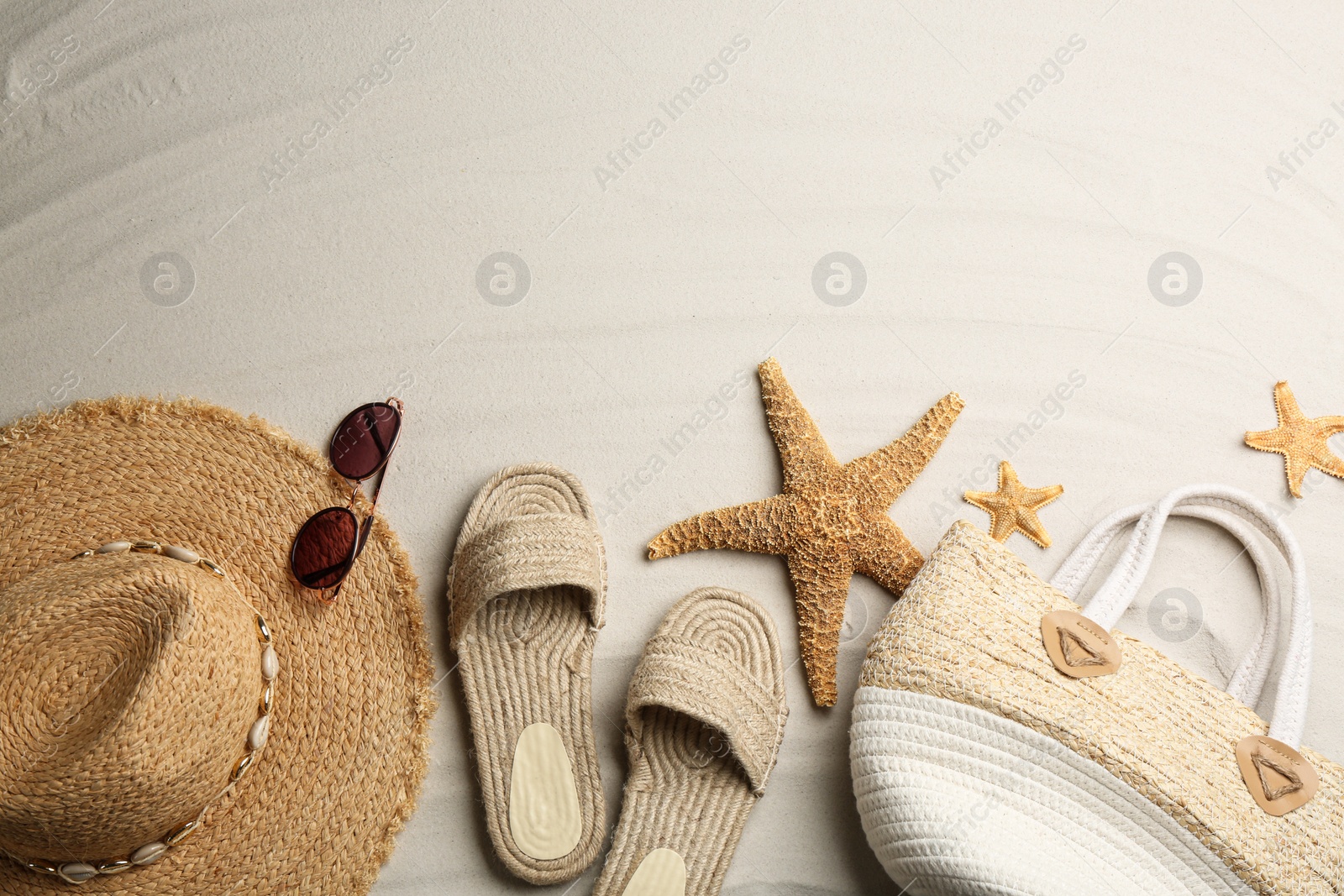 Photo of Different beach accessories on sand, flat lay. Space for text