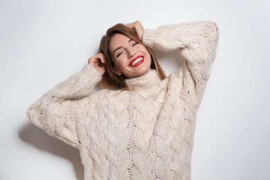 Beautiful young woman in warm sweater on white background