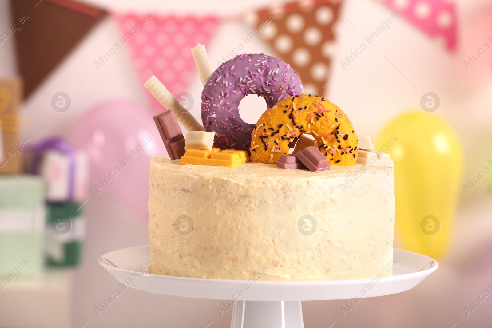Photo of White stand with delicious cake decorated with sweets against blurred background, closeup