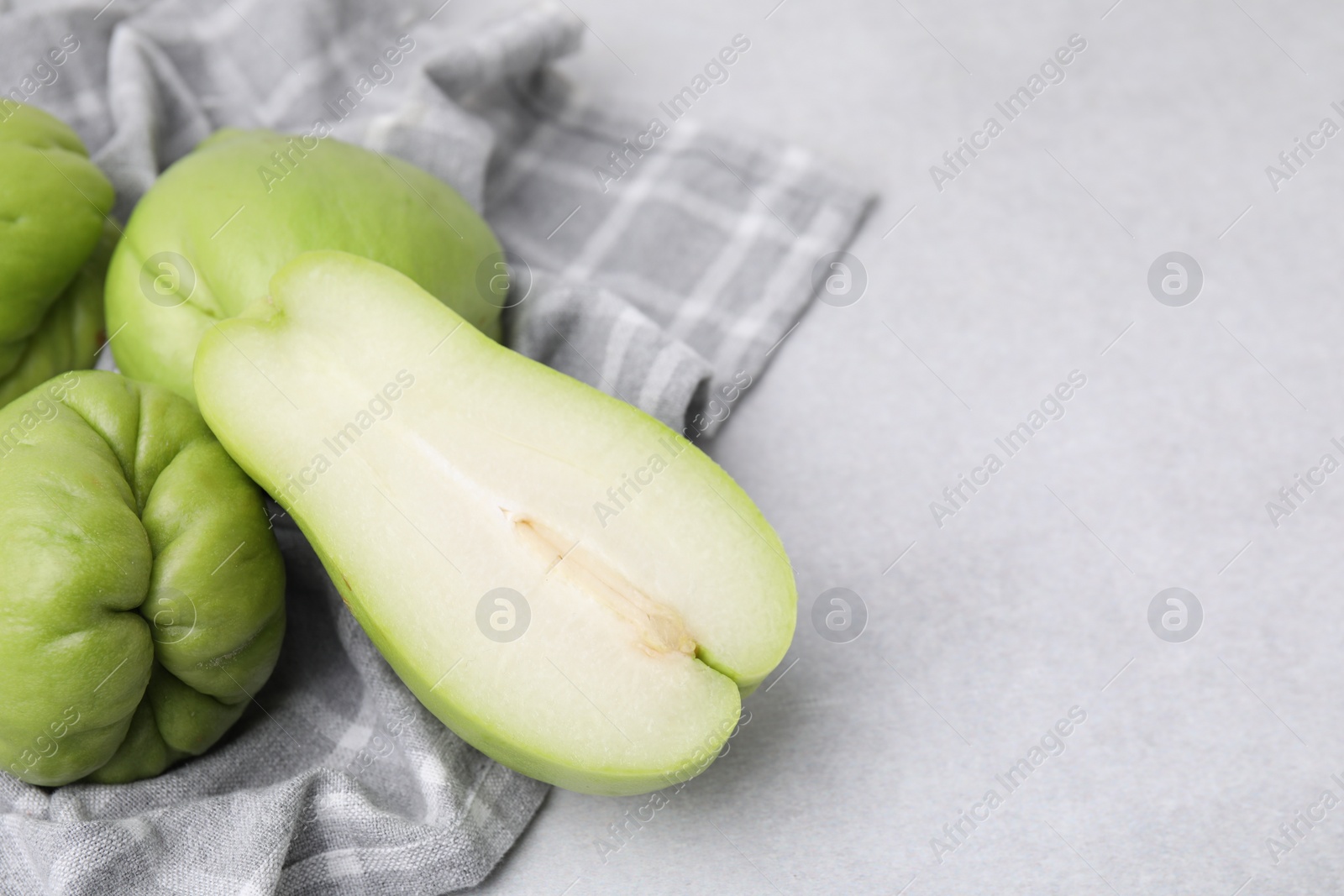 Photo of Cut and whole chayote on gray table, closeup. Space for text