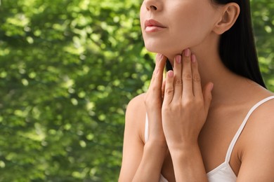 Photo of Young woman doing thyroid self examination near window, closeup. Space for text