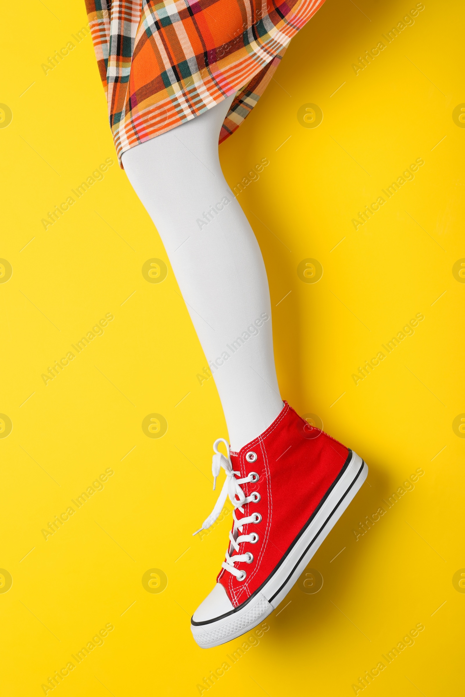 Photo of Woman wearing shoes on yellow background, closeup