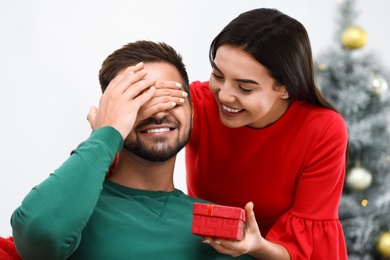 Young woman giving Christmas gift to her boyfriend at home