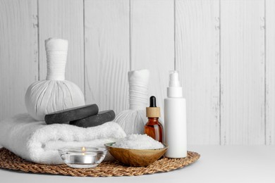 Composition with different spa products and candle on white table against wooden background. Space for text