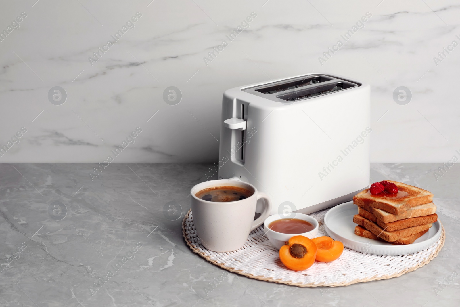 Photo of Toaster, roasted bread, coffee and apricot jam on gray marble table, space for text. Tasty breakfast