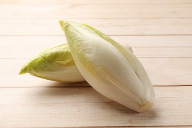 Photo of Raw ripe chicories on wooden table, closeup