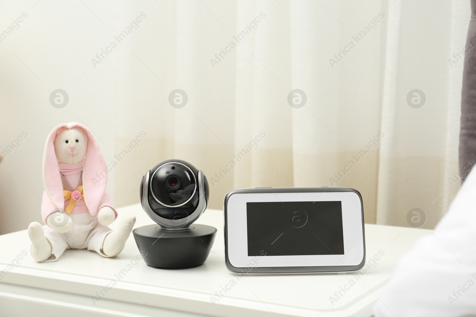 Photo of Baby monitor with camera and toy on table in room. Video nanny