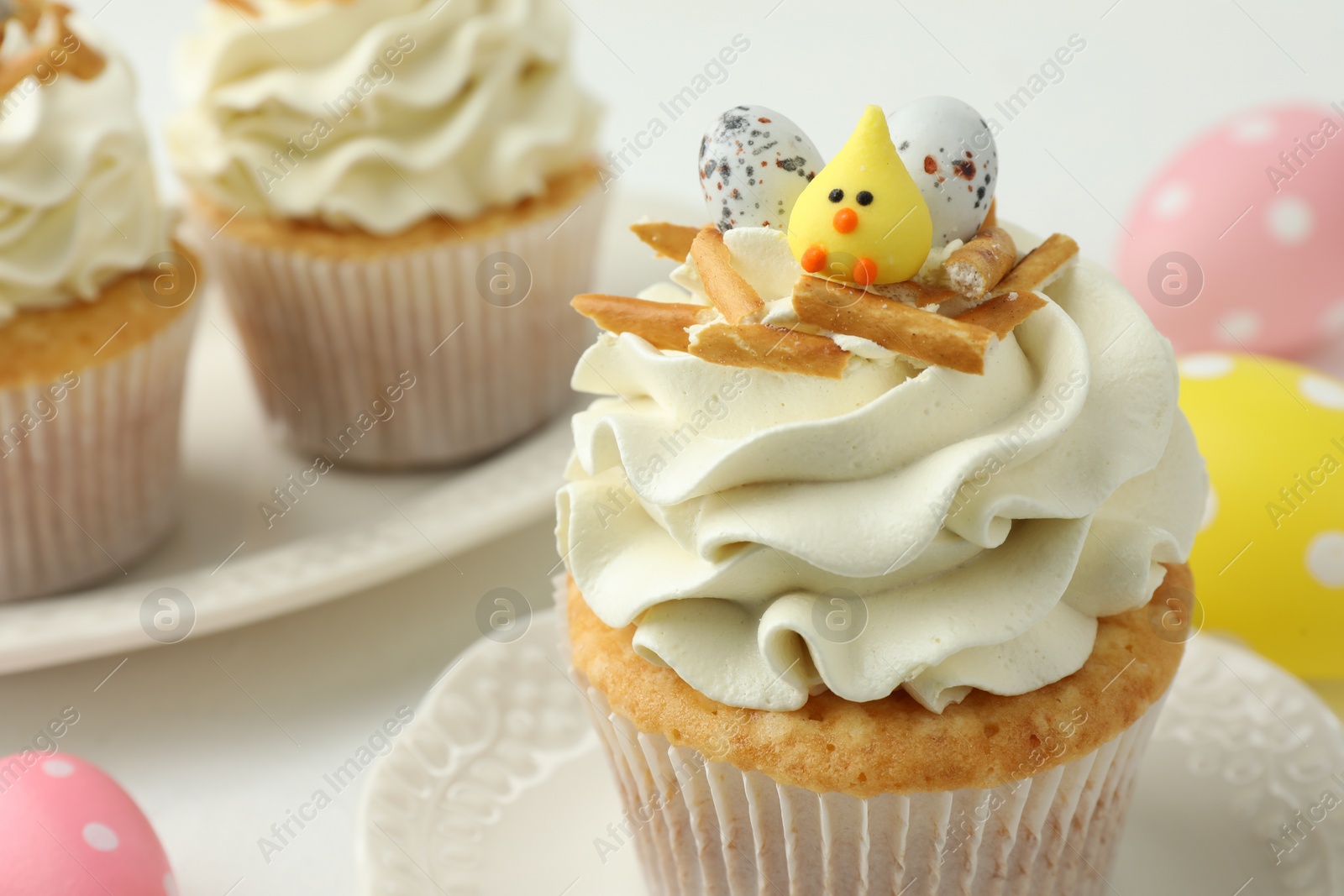 Photo of Tasty Easter cupcakes with vanilla cream on white table, closeup