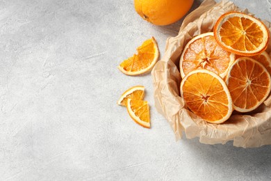 Photo of Many dry orange slices and fresh fruit on grey textured table, flat lay. Space for text