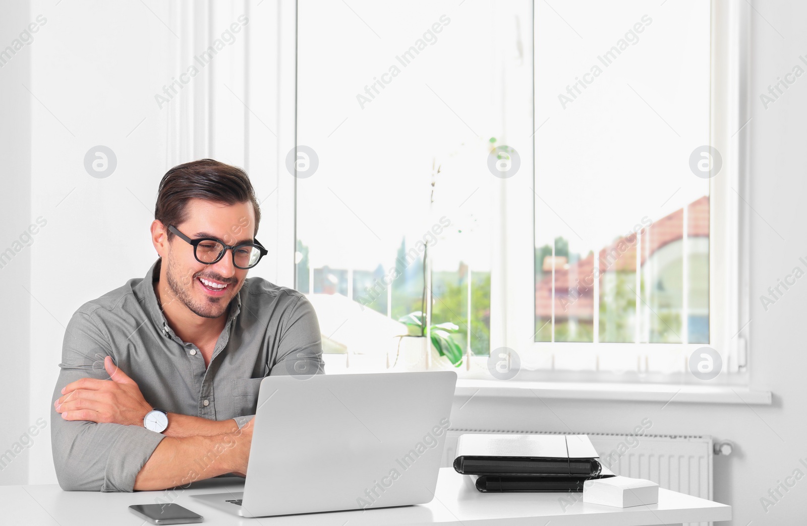 Photo of Handsome young man working with laptop at table in office