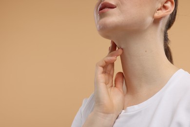 Photo of Woman touching her neck on beige background, closeup. Space for text