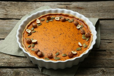 Photo of Delicious pumpkin pie with seeds and hazelnuts on wooden table
