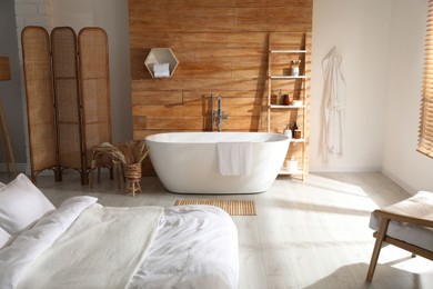 Photo of Stylish apartment interior with white bathtub and bed