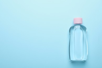 Bottle of baby oil on light blue background, top view. Space for text