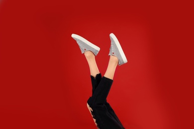 Woman in stylish sport shoes on red background