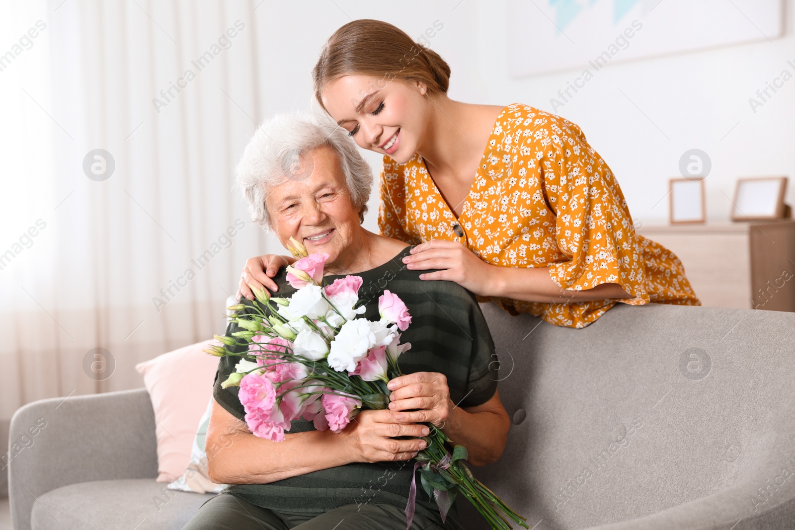 Photo of Young woman congratulating her senior mom at home. Happy Mother's Day