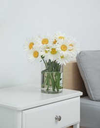 Photo of Bouquet of beautiful daisy flowers on nightstand in bedroom