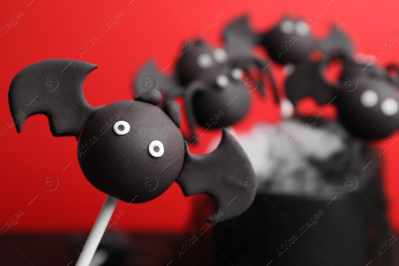 Photo of Delicious Halloween themed cake pops on red background, closeup. Space for text