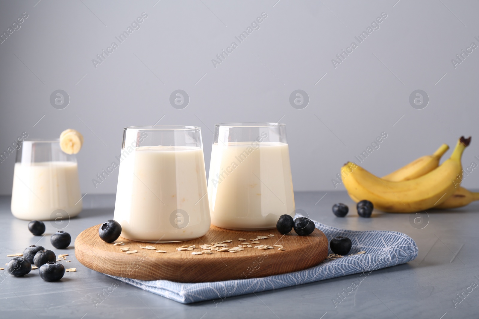 Photo of Tasty yogurt in glasses, oats and blueberries on grey table