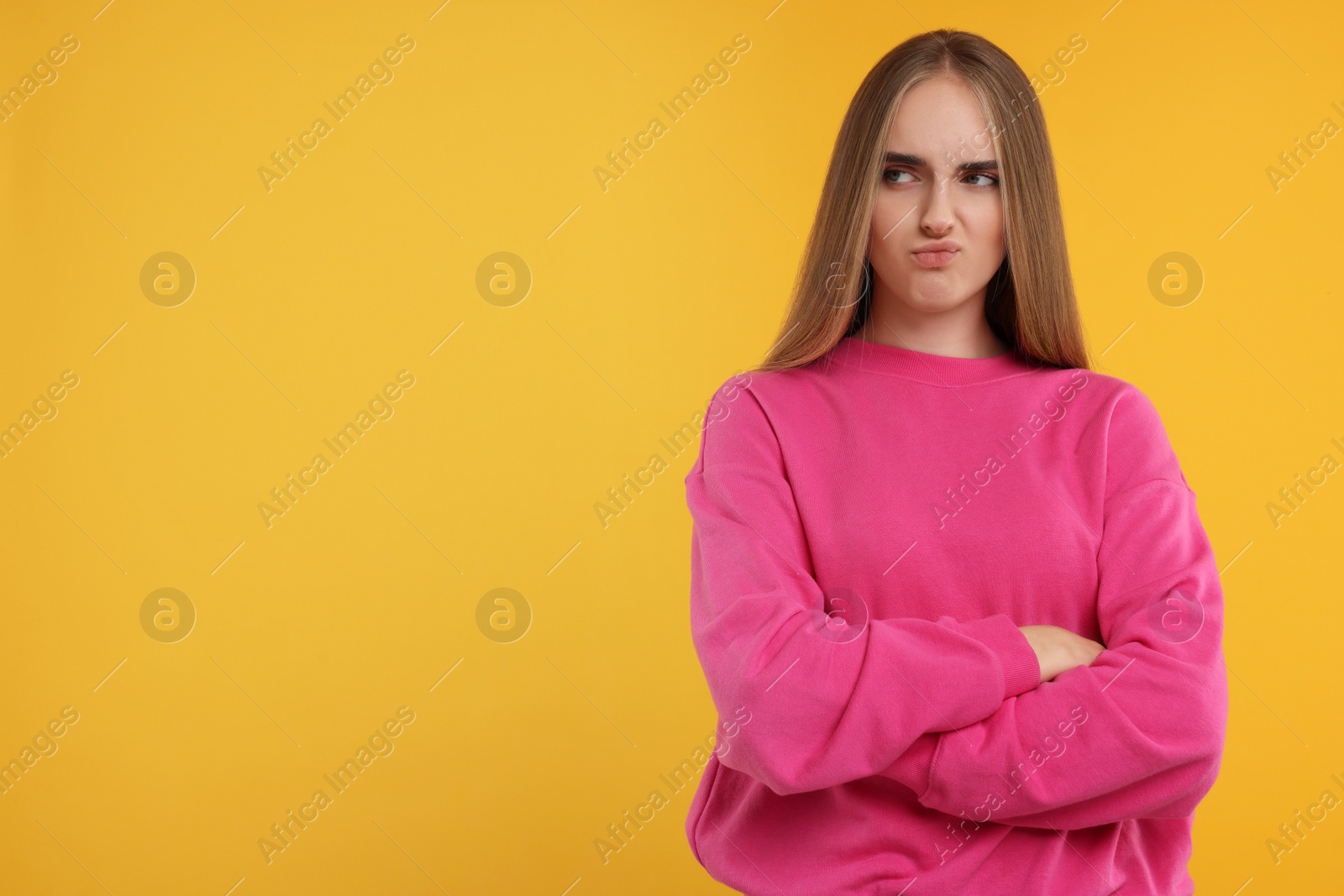 Photo of Resentful woman with crossed arms on orange background, space for text