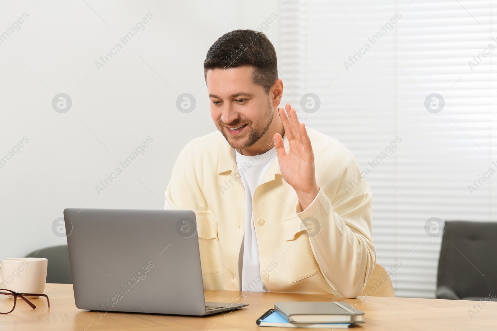 Photo of Man having video chat via laptop at wooden table at home