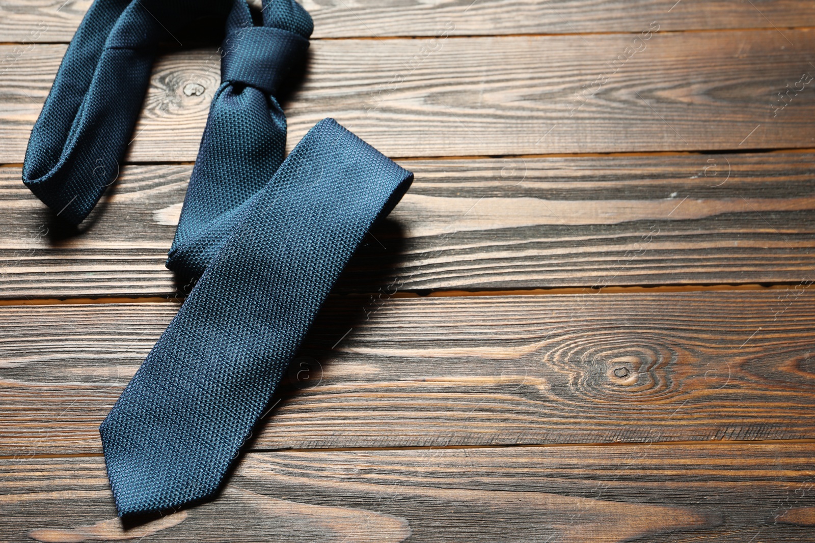 Photo of One blue necktie on wooden table, top view. Space for text