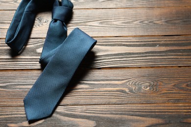 One blue necktie on wooden table, top view. Space for text