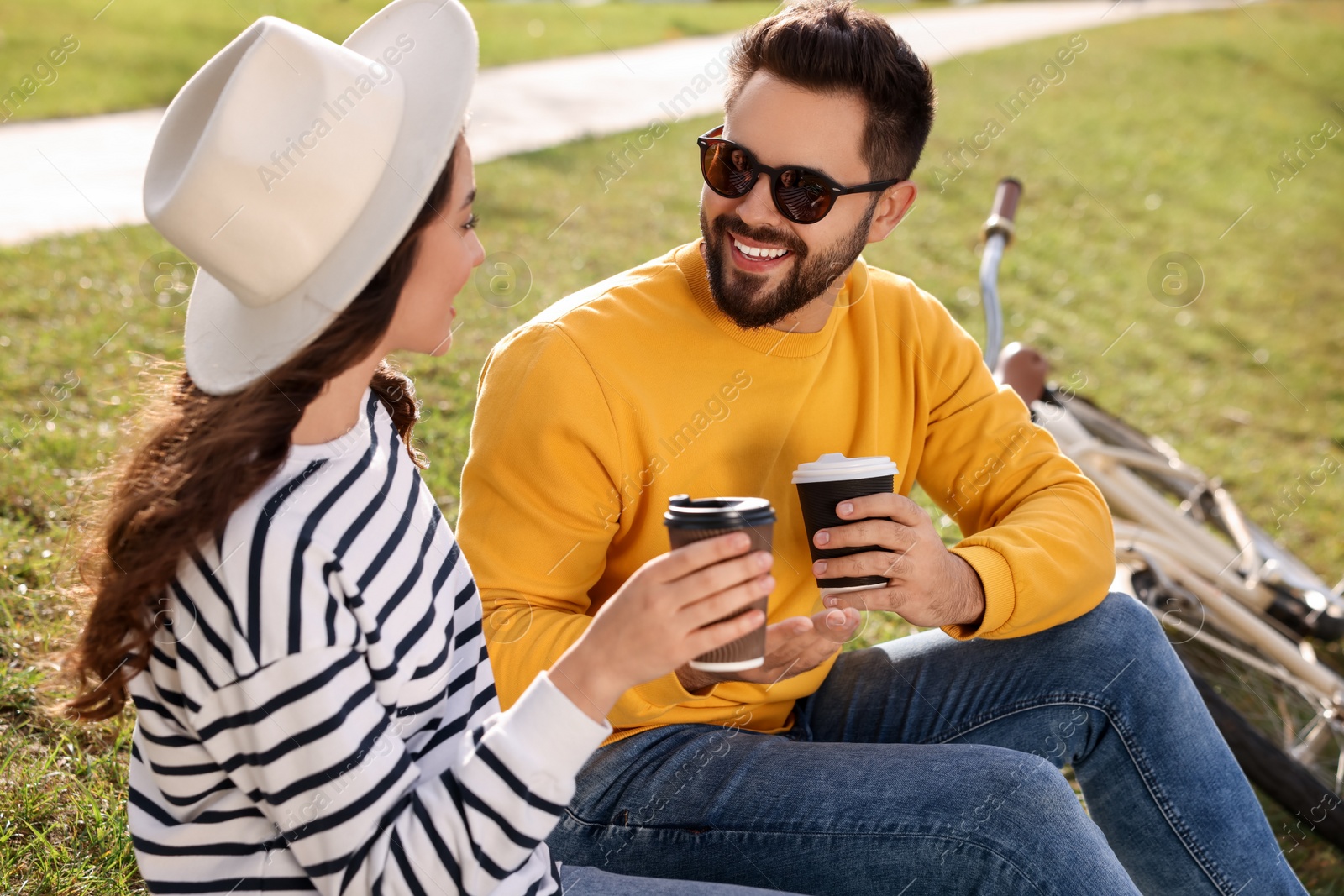 Photo of Beautiful young couple with takeaway coffee spending time together outdoors