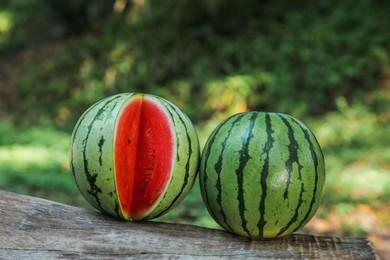 Delicious whole and cut watermelons on log outdoors